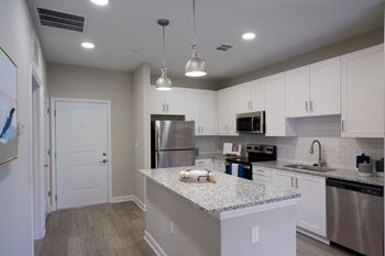 A kitchen with a granite countertop and stainless steel appliances.
